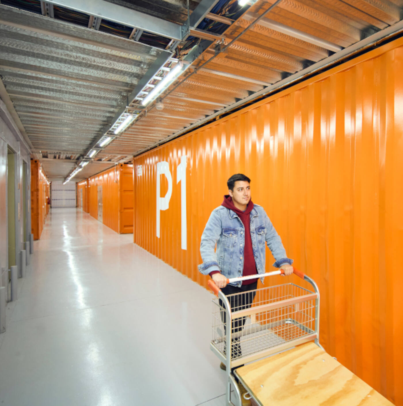 Operación de minibodegas: pasillo con puertas naranjas y carro de traslado